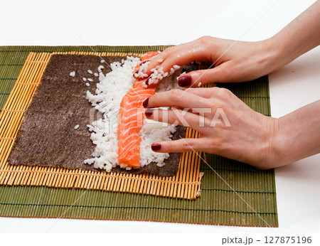 Female hands rolling salmon sushi 127875196