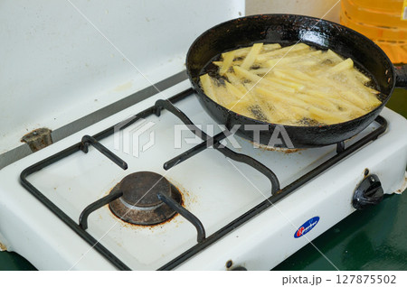 海外の家庭のコンロで揚げるフライドポテト 127875502