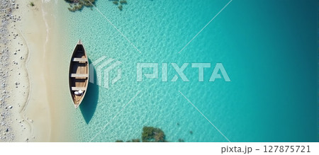 Serene aerial view of a tranquil beach, featuring a boat resting by the crystal-clear blue waters 127875721