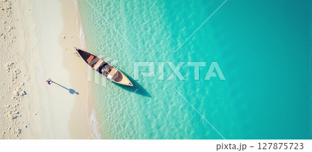 Serene aerial view of a tranquil beach, featuring a boat resting by the crystal-clear blue waters 127875723