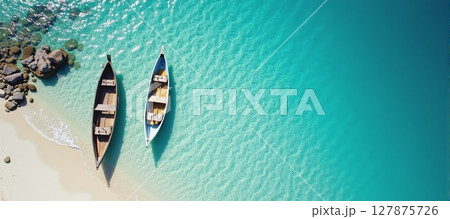 Serene aerial view of a tranquil beach, featuring a boat resting by the crystal-clear blue waters 127875726