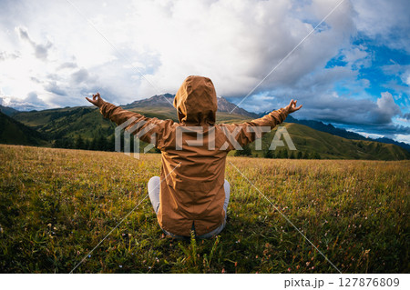 Woman hiker meditation on the high altitude mountain top grassland Woman hiker meditation on the high altitude mountain top grassland 127876809