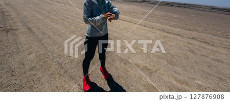 Woman trail runner set the sports watch cross country running on desert Woman trail runner set the sports watch cross country running on desert 127876908