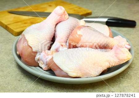 Raw chicken legs with pepper and spices on a board and plate ready for Raw chicken legs with pepper and spices on a board and plate ready for 127878241