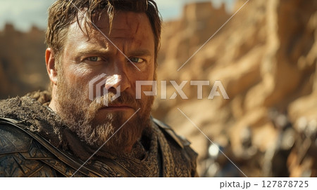 medieval king stands tall amidst castle ruins, his battle worn armor partly hidden flowing cloak his sword is thrust into stone as he gazes forward, filled grief and resolve 127878725