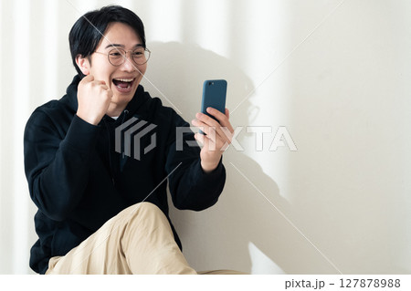 壁際でスマホを見る男性 壁際でスマホを見る男性 127878988