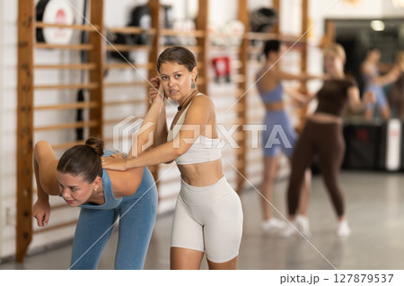 Young woman twisting her opponent's arm during self-defense classes 127879537