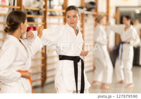 Young female attendee of karate classes fighting with partner in sports hall 127879590