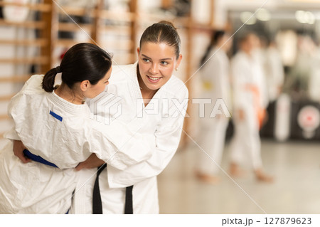 Positive young girl applying throwing technique during judo classes 127879623