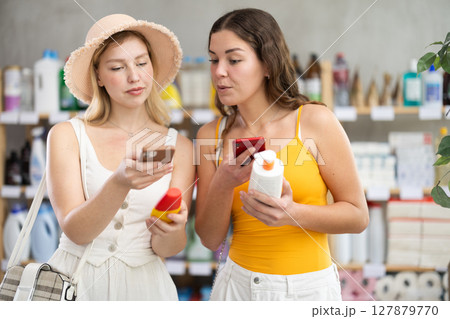 Two friends girls buyer scans qr code on sunblock cream label Two friends girls buyer scans qr code on sunblock cream label 127879770