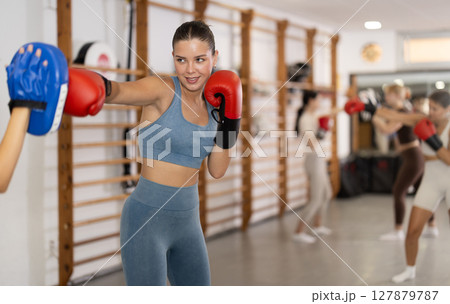 Woman works out strength and speed of boxing punch mitts with help of partner in boxing paws Woman works out strength and speed of boxing punch mitts with help of partner in boxing paws 127879787
