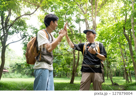 Father and Son Celebrating Together. Sharing a high-five in a vibrant outdoor setting. Father and Son Celebrating Together. Sharing a high-five in a vibrant outdoor setting. 127879804