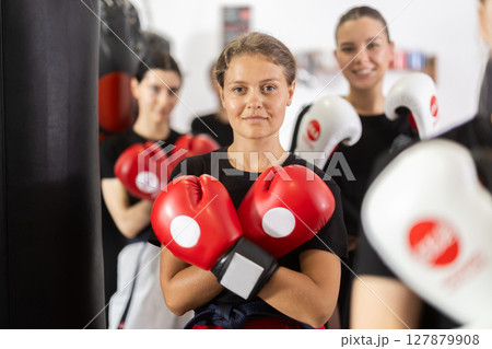 Girl coach in boxing gloves is standing in gym Girl coach in boxing gloves is standing in gym 127879908