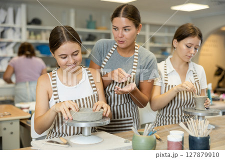 Female teacher explaining to students how to sculpt ceramics Female teacher explaining to students how to sculpt ceramics 127879910