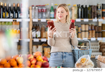 Girl shopping at supermarket - choosing ketchup in grocery supermarket 127879957
