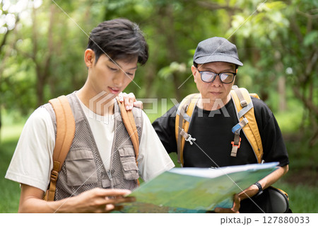 Father and Son Hiking Adventure. Exploring nature together with a map. 127880033