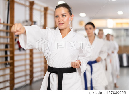 Young woman practicing punches standing in row with others 127880066