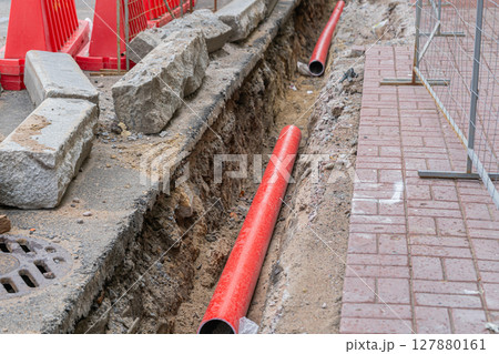 Road repairs, pipe, pile of sand. Red and white plastic barriers blocking the road. Road repairs, pipe, pile of sand. Red and white plastic barriers blocking the road. 127880161