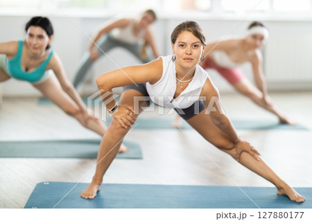 Young woman during Pilates strength training standing performs exercises 127880177