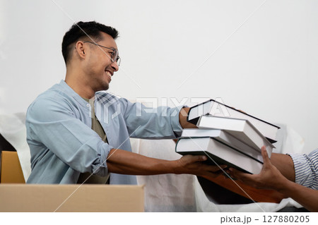 Gay couple sharing joyful moments while unpacking boxes together 127880205