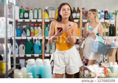 Woman scrolling through shopping list on phone in supermarket Woman scrolling through shopping list on phone in supermarket 127880209