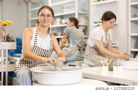 Woman teacher and students make products on potter's wheel 127880220