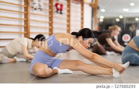 Young girl doing leg stretching in group 127880293