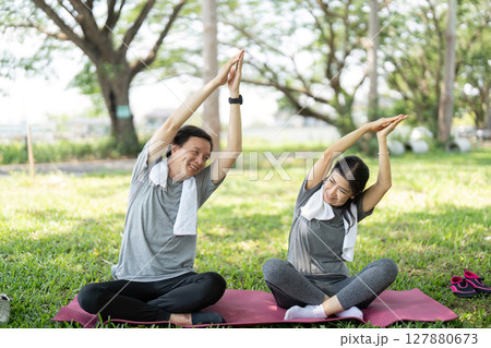 Couple enjoying outdoor yoga stretches in a park 127880673