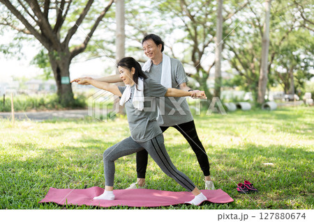 Couple practicing yoga poses together in the park 127880674