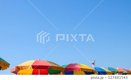 鮮やかなビーチパラソルと広い青空 127881543