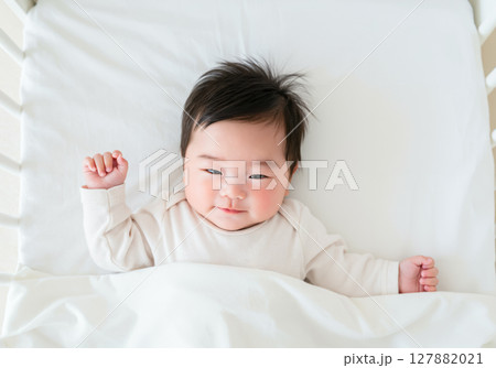 ベビーベッドで目を覚ました赤ちゃん 127882021