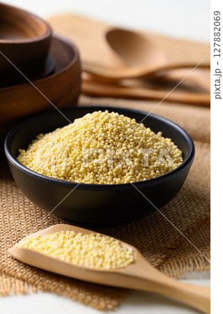 Yellow millet grain in black bowl with scoop, Food ingredient Yellow millet grain in black bowl with scoop, Food ingredient 127882069