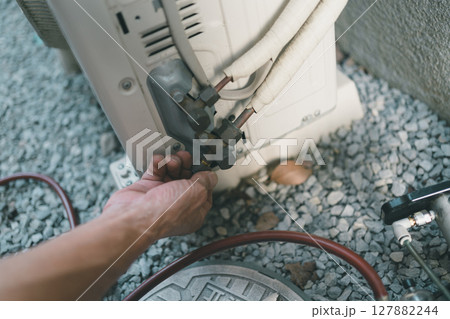 エアコン室外機のサービスポートのキャップを手で仮締めする 127882244