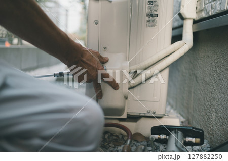 エアコン室外機の電装カバーを外すエアコン業者 127882250