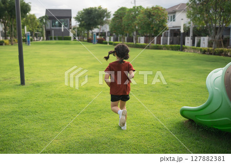 Joyful Child Running in Park with Vibrant Green Grass and Play Equipment, Bright Sunny Day, Outdoor Activity, Happiness and Freedom Experience 127882381