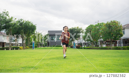Happy child running joyfully in a lush green park, enjoying a sunny day of outdoor fun, showcasing freedom, energy, and vibrant childhood moments 127882382