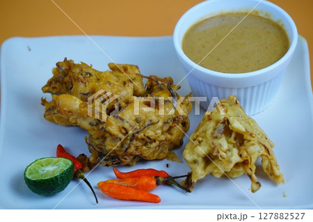 A plate of Bakwan or golden-brown Indonesian fritters served with a dipping sauce, lime, and chili peppers. A plate of Bakwan or golden-brown Indonesian fritters served with a dipping sauce, lime, and chili peppers. 127882527