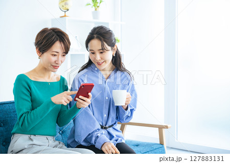 モダンなリビングでスマホを見る二人の女性 127883131