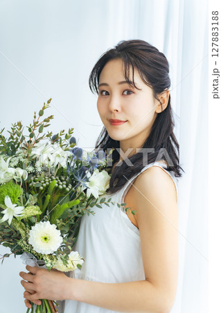 ナチュラルブーケを持った白いワンピースの女性 127883188
