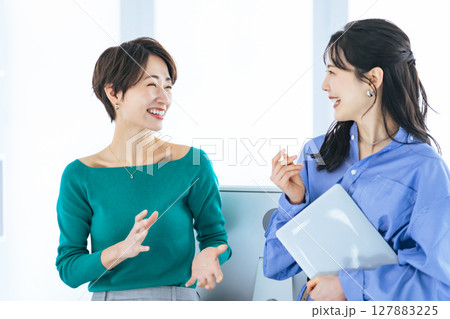 モダンなオフィスで会話する二人の女性 モダンなオフィスで会話する二人の女性 127883225
