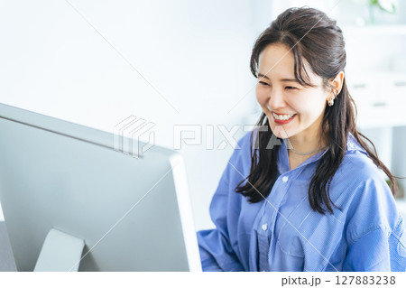 モダンなオフィスでPCモニターを見ながら作業する女性 モダンなオフィスでPCモニターを見ながら作業する女性 127883238