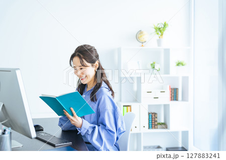 モダンなオフィスでPCモニターを見ながら作業する女性 127883241