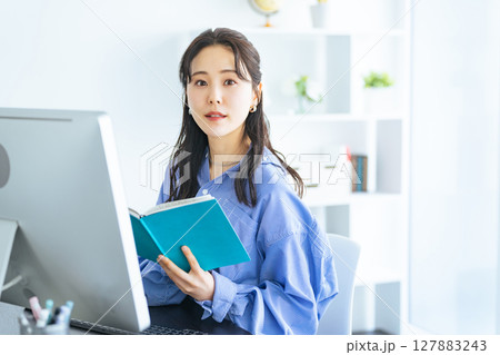 モダンなオフィスでPCモニターを見ながら作業する女性 127883243