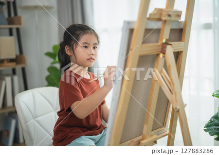 Young Girl Engaged in Creative Art Activity Painting on Canvas in Bright Indoor Space with Natural Light and Relaxing Atmosphere Young Girl Engaged in Creative Art Activity Painting on Canvas in Bright Indoor Space with Natural Light and Relaxing Atmosphere 127883286