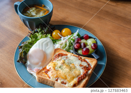 チーズトーストと目玉焼き、サラダが並ぶ洋風の朝食プレート 127883463