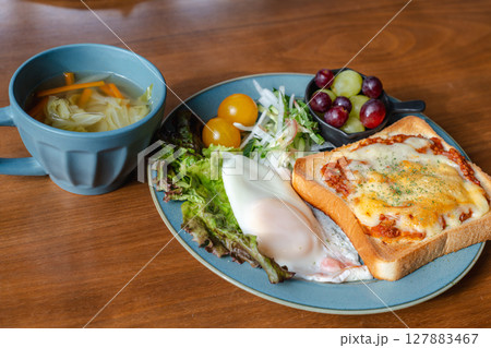 チーズトーストと目玉焼き、サラダが並ぶ洋風の朝食プレート チーズトーストと目玉焼き、サラダが並ぶ洋風の朝食プレート 127883467