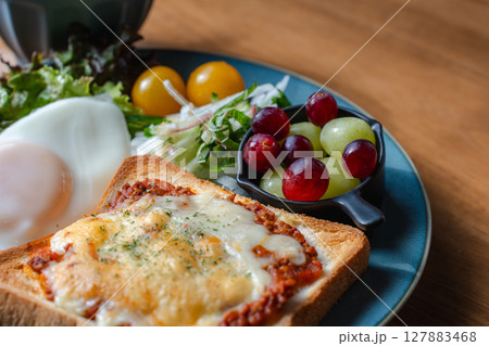 チーズトーストと目玉焼き、サラダが並ぶ洋風の朝食プレート チーズトーストと目玉焼き、サラダが並ぶ洋風の朝食プレート 127883468
