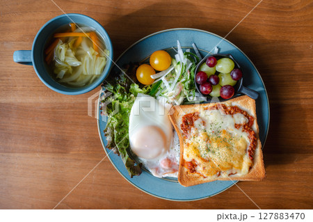 チーズトーストと目玉焼き、サラダが並ぶ洋風の朝食プレート チーズトーストと目玉焼き、サラダが並ぶ洋風の朝食プレート 127883470