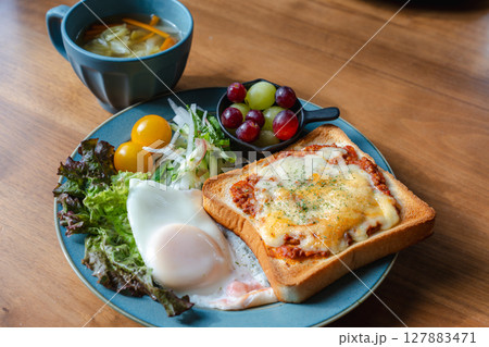 チーズトーストと目玉焼き、サラダが並ぶ洋風の朝食プレート 127883471