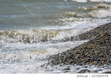 Sea water splashing over the stones on the beach Sea water splashing over the stones on the beach 127884376